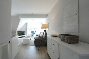 Una sala de estar moderna con televisión, un trípode, una lámpara y un cartel en la pared.