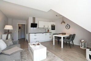 Un apartamento moderno con comedor, cocina y sala de estar con sofá y lámpara.