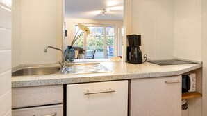 Una cocina moderna con armarios blancos, encimera de granito, cafetera y vistas al exterior.