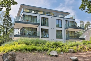 A modern multi-story house with large windows, balconies, and a well-maintained garden. - Villa Stern Appartement 2 (Timmendorfer Strand)