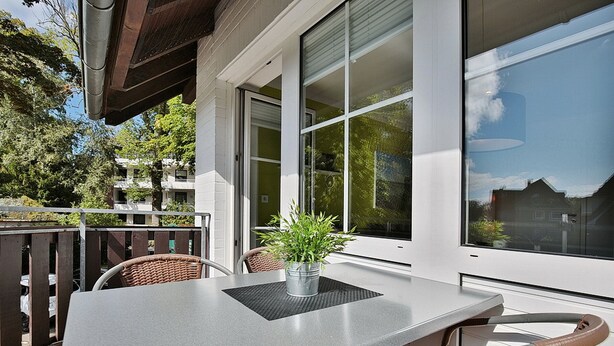 Ein Balkon mit Tisch, Stühlen, einer Topfpflanze und Blick auf die Umgebung.