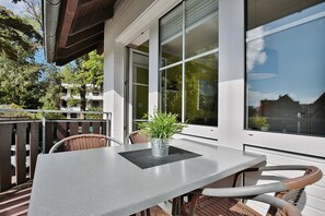 Un balcon avec une table et des chaises, un pot de fleurs et une vue sur les environs.
