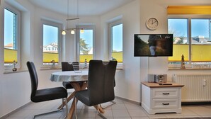 Ein moderner Essbereich mit einem runden Tisch, schwarzen Stühlen und einem Fernseher auf einem Schrank.