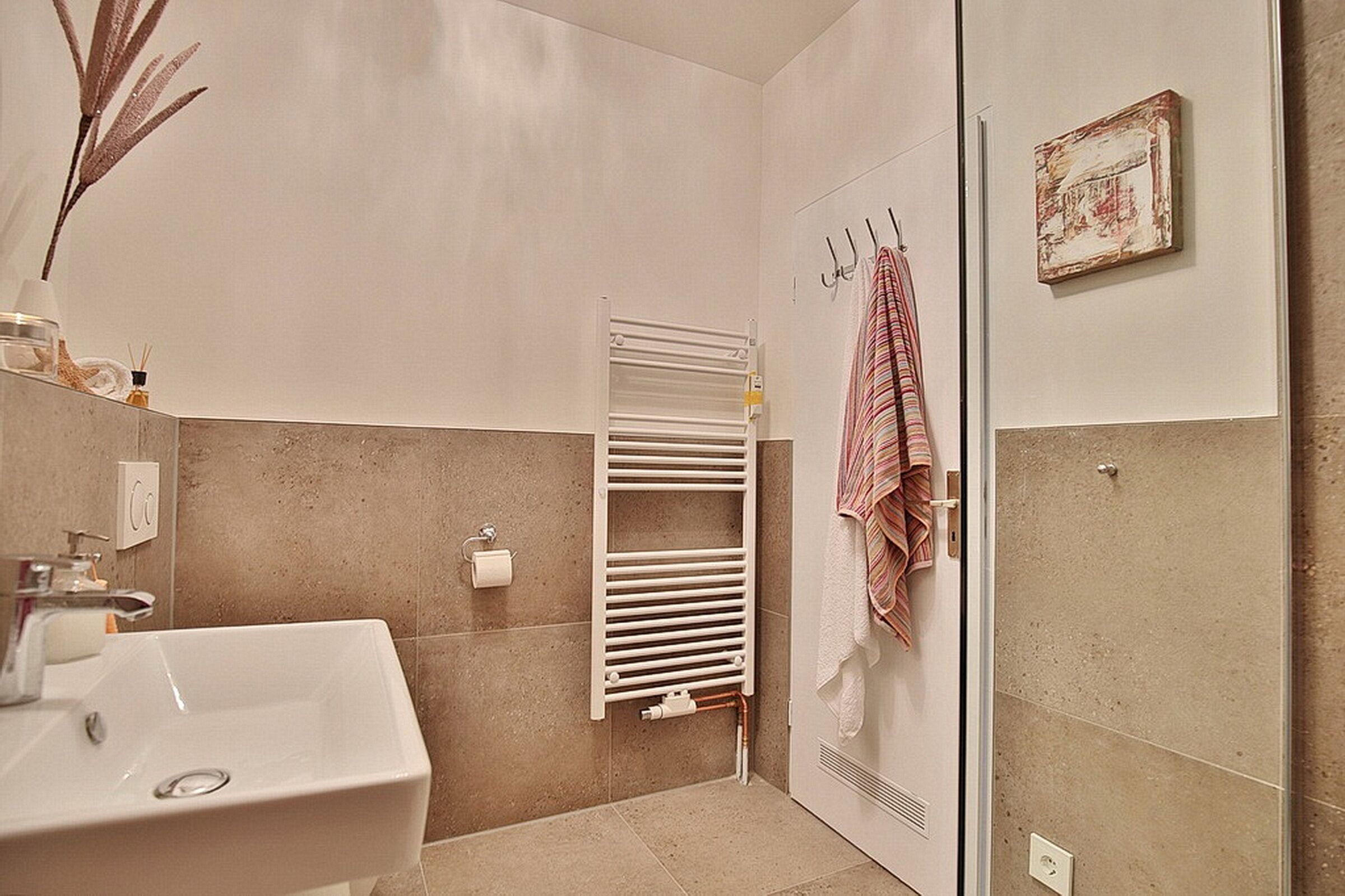 A modern bathroom with a white sink, towel rack, and a radiator.
