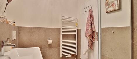 A modern bathroom with a white sink, towel rack, and a radiator.