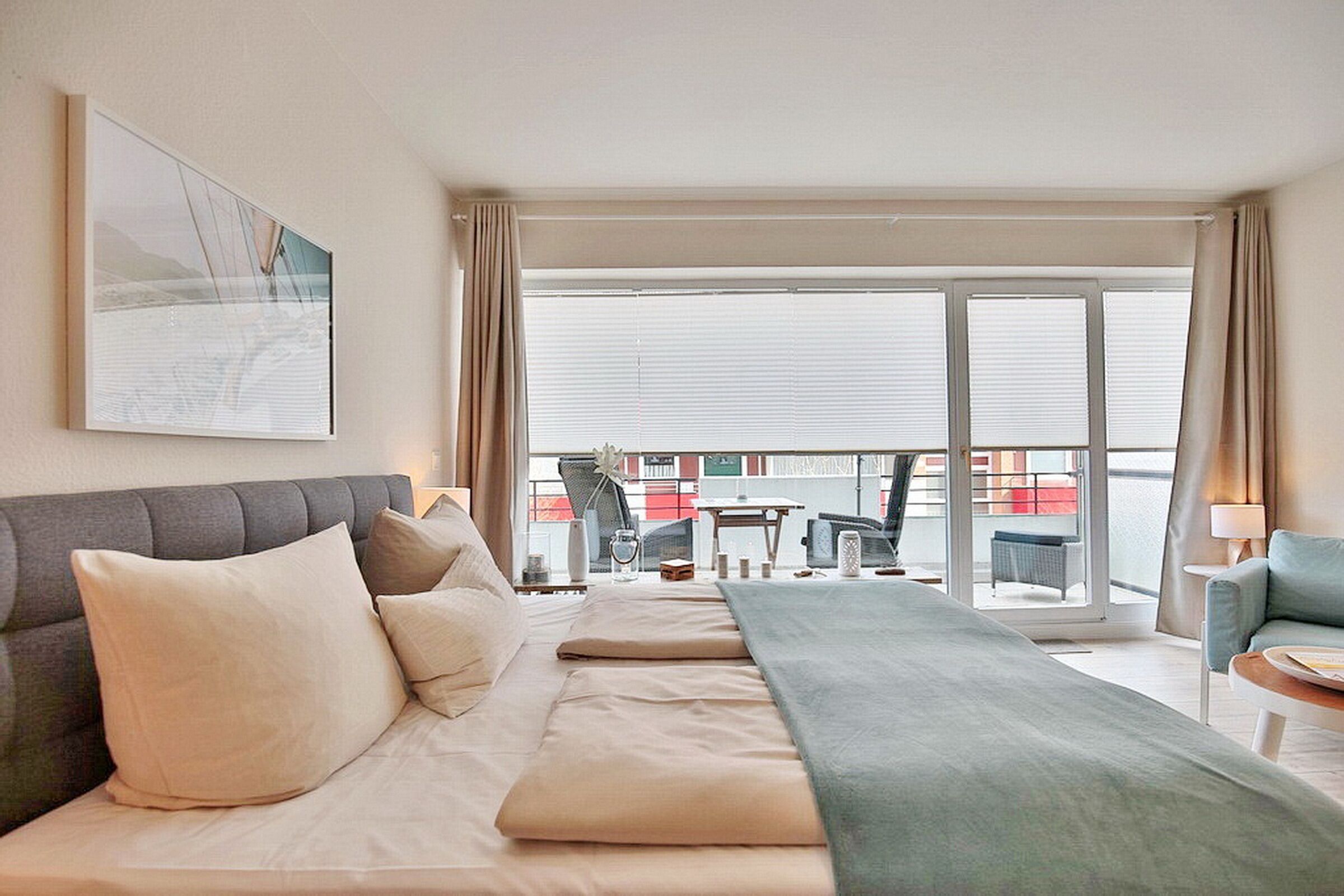 Habitación de hotel con cama, escritorio, silla y balcón con vistas.