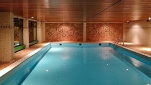 Une piscine dotée d’un plafond en bois et de carreaux muraux à motifs.