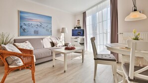 Ein modernes Wohnzimmer mit einer Couch, einem Esstisch und einem Fernseher.