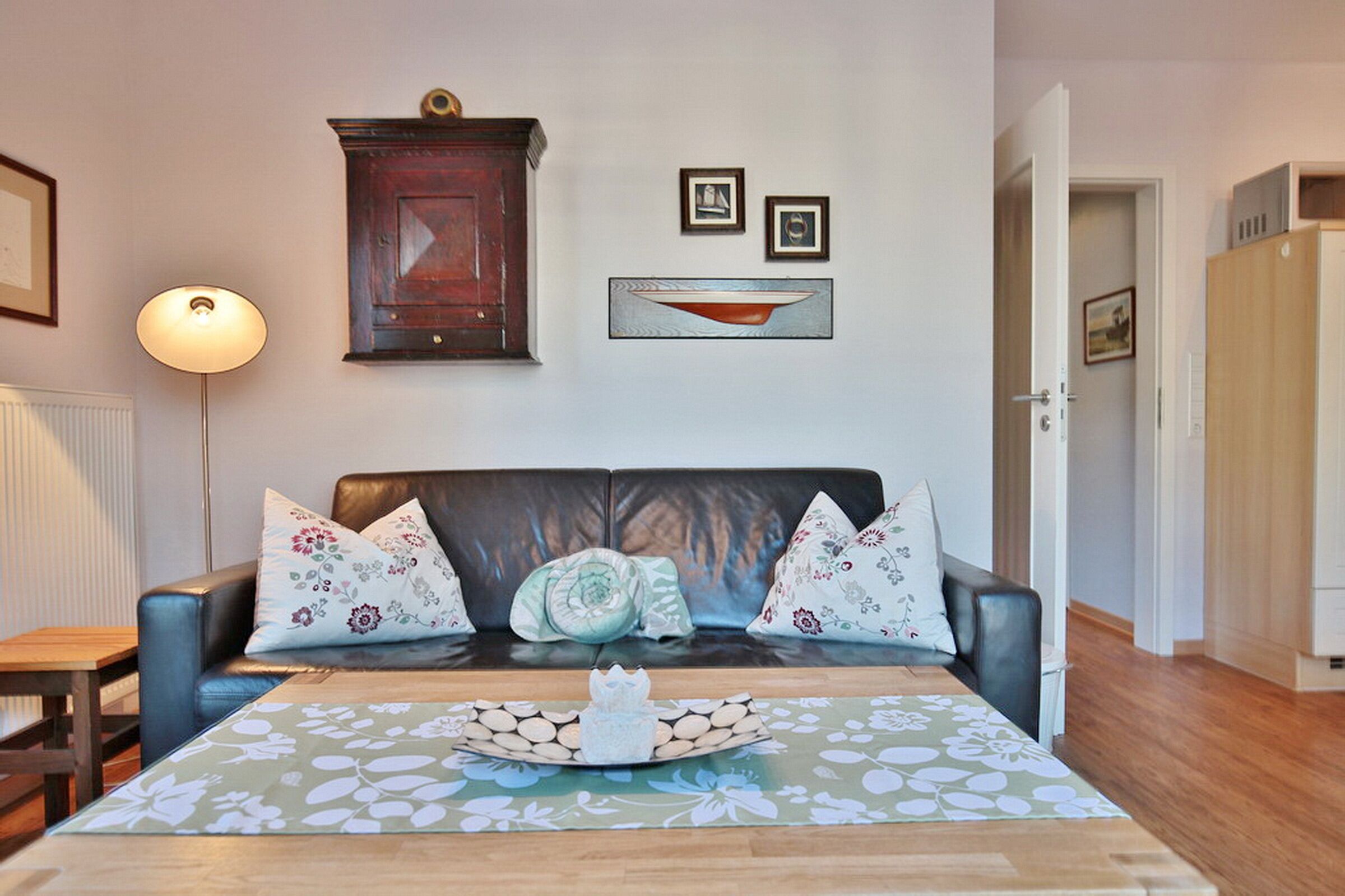 A living room with a sofa, a table with a decorative tray, a lamp, and a cabinet.