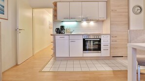 A modern kitchen with white cabinets, a built-in oven, and a coffee maker.