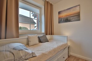 Quarto com cama, janela, um quadro e vista para o exterior.