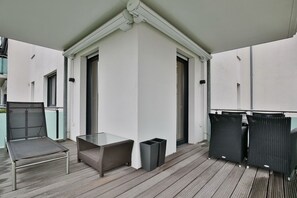 Ett takförsett utomhusområde med ett glasbord, en flätstol och två svarta stolar.