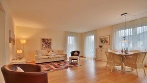 Un salon spacieux comprenant un canapé, une table à manger avec des chaises et une petite table d’appoint.