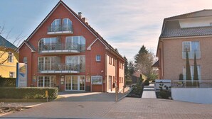 Un bâtiment en briques rouges doté d’un balcon, d’une enseigne indiquant la réception et d’un chemin piétonnier dallé.