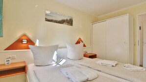 Ein Hotelzimmer mit einem Bett, Kissen, einem Nachttisch mit Lampe, einem Wandbild und einem Kleiderschrank.