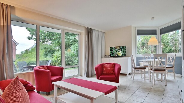 Una sala de estar moderna con un sofá, sillones, una mesa de comedor y un televisor.