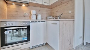 Una cocina compacta con horno integrado, cafetera y lavavajillas.