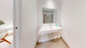 A modern bathroom with a white sink, mirror, and towel rack. - One Bedroom Apartment (Toledo)