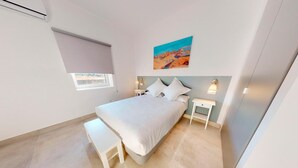 A bedroom with a bed, bedside tables, a bench, a window with a blind, and a painting on the wall. - One Bedroom Apartment (Toledo)