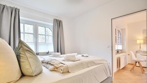 Een moderne slaapkamer met een net opgemaakt bed, een nachtkastje en uitzicht op de aangrenzende badkamer.