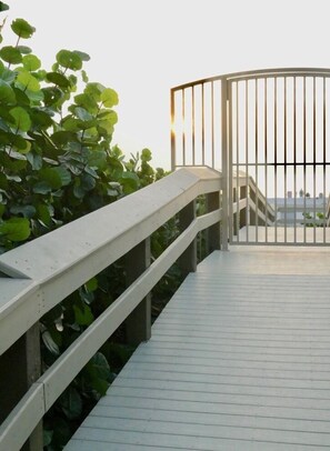 A wooden deck with a metal gate leading to a building. - Charming 2 Bed South End Beachfront Condo at Popular Seawinds (Marco Island)