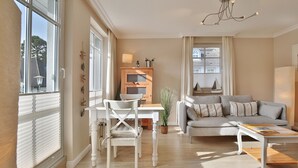 Een ruime woonkamer met een bank, salontafel en een eethoek met tafel en stoelen.
