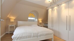 Een slaapkamer met een bed, een garderobe en twee nachtkastjes met lampen.