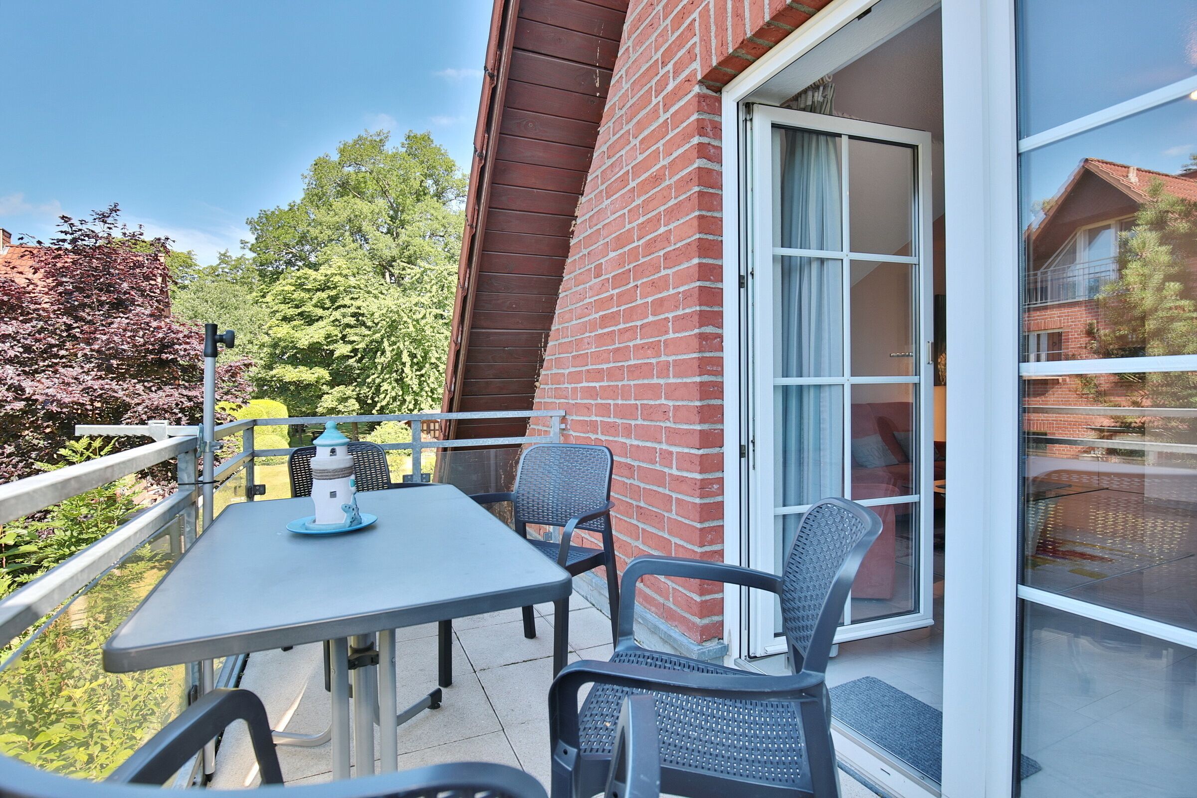 A balcony with a table and chairs, a small decorative item, and a glass door leading to a room.