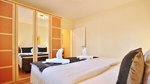 Ein Hotelzimmer mit einem großen Bett, einem Schrank mit Schiebetüren, einem Nachttisch und einem Spiegel.