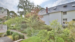 Ein Wohngebiet mit einem weißen Haus, einer überdachten Sitzterrasse und einem Garten mit verschiedenen Pflanzen und Bäumen.