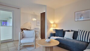 Una sala de estar con un sofá, una mesa redonda de madera, una silla y una lámpara.