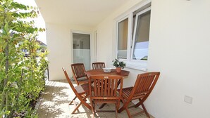Un patio con una mesa y sillas de madera, una planta en maceta y una ventana.