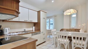 Una cocina moderna con estufa integrada, armarios blancos y un comedor con sillas y banco blancos.