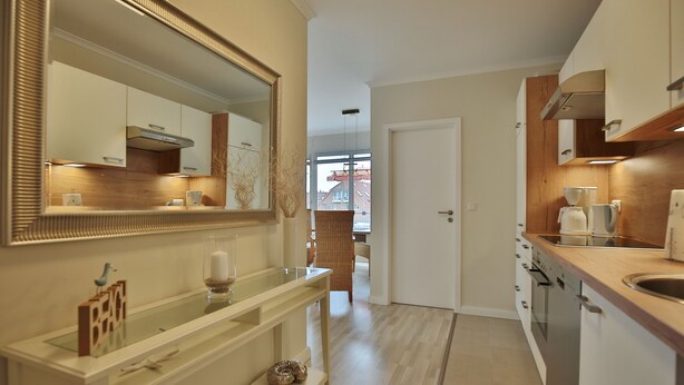A modern kitchen with a large mirror, wooden cabinets, and a built-in oven.