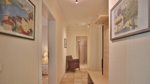 A hallway with a bench, a chair, and a door leading to a bathroom. - Moderne Strandvilla Appartement 2 (Timmendorfer Strand)