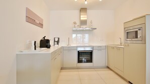 A modern kitchen with white cabinetry, a built-in oven, a microwave, and a coffee machine. - Villa Mér Baltique Appartement 13 (Timmendorfer Strand)