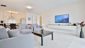 A modern living room with grey sofas, a coffee table, and a flat-screen TV mounted on the wall. - Villa Mér Baltique Appartement 13 (Timmendorfer Strand)