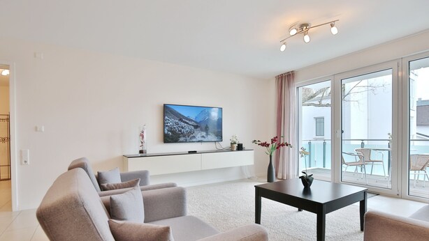 A modern living room with a sofa, a coffee table, and a flat-screen TV mounted on the wall. - Villa Mér Baltique Appartement 13 (Timmendorfer Strand)