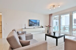 Un salon moderne avec un canapé, une table basse et un téléviseur à écran plat fixé au mur.