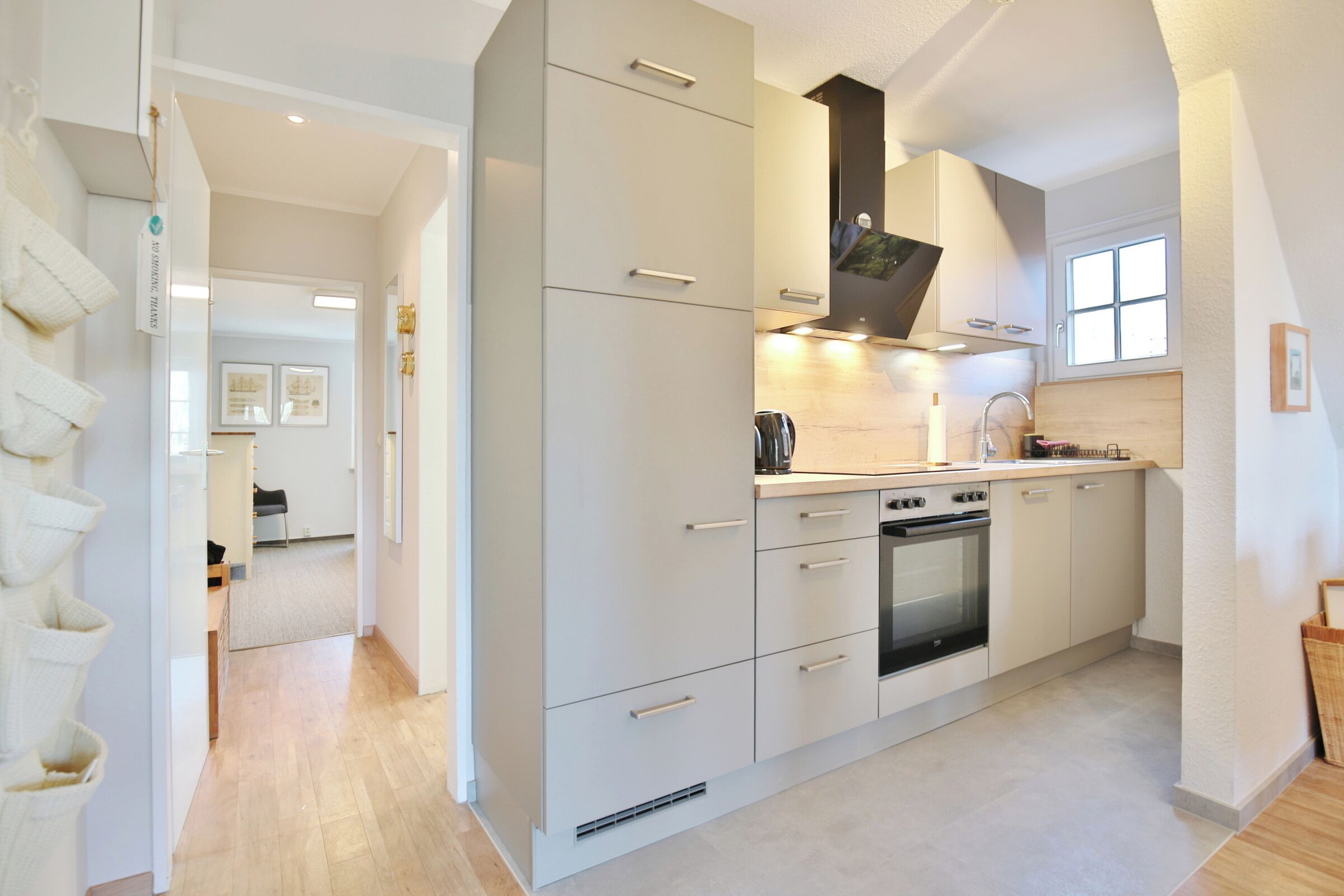 A modern kitchen with white cabinetry, a built-in oven, and a window above the sink.
