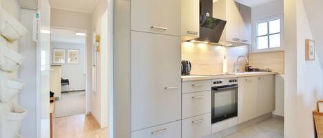A modern kitchen with white cabinetry, a built-in oven, and a window above the sink.