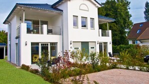Una casa a due piani con un balcone, un garage e un giardino curato.