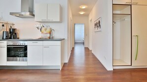 Una cucina moderna con mobili bianchi, elettrodomestici in acciaio inossidabile e pavimento in legno.