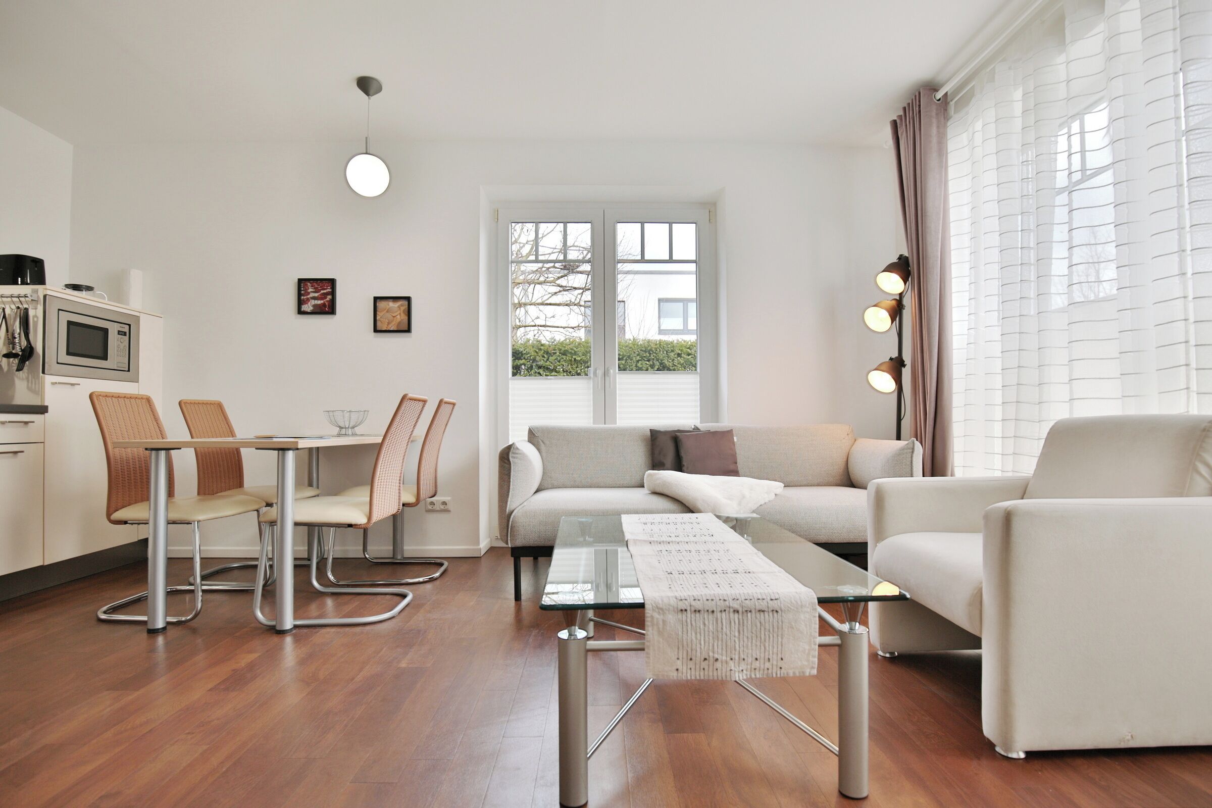 A modern living room with a glass coffee table, a sofa, and a dining area with chairs.