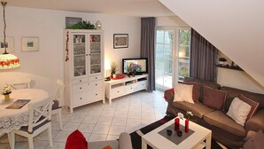 En moderne stue med spiseområde, et fjernsyn og en trappe til en etage ovenover.
