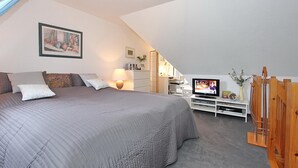 Et soveværelse med en stor seng, et fjernsyn, et skrivebord og en stol.