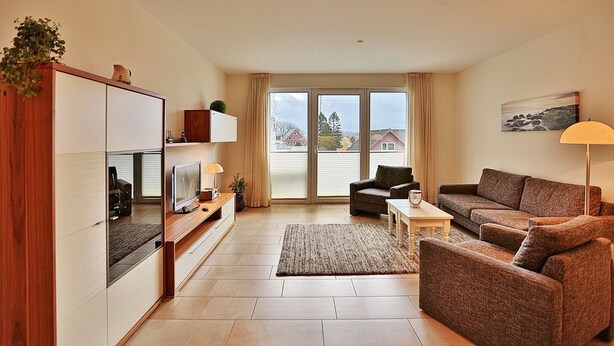 A modern living room with a sofa set, a TV, and a wooden cabinet. - Villa Mér Baltique Appartement 20 (Timmendorfer Strand)