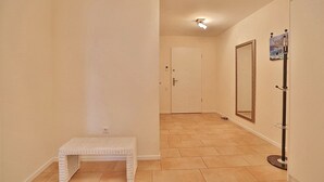 A hallway with a bench, a coat rack, and a door in the distance. - Villa Mér Baltique Appartement 20 (Timmendorfer Strand)