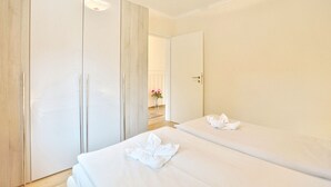 Een hotelkamer met twee bedden, een kledingkast en een badkamer die door een geopende deur zichtbaar is.
