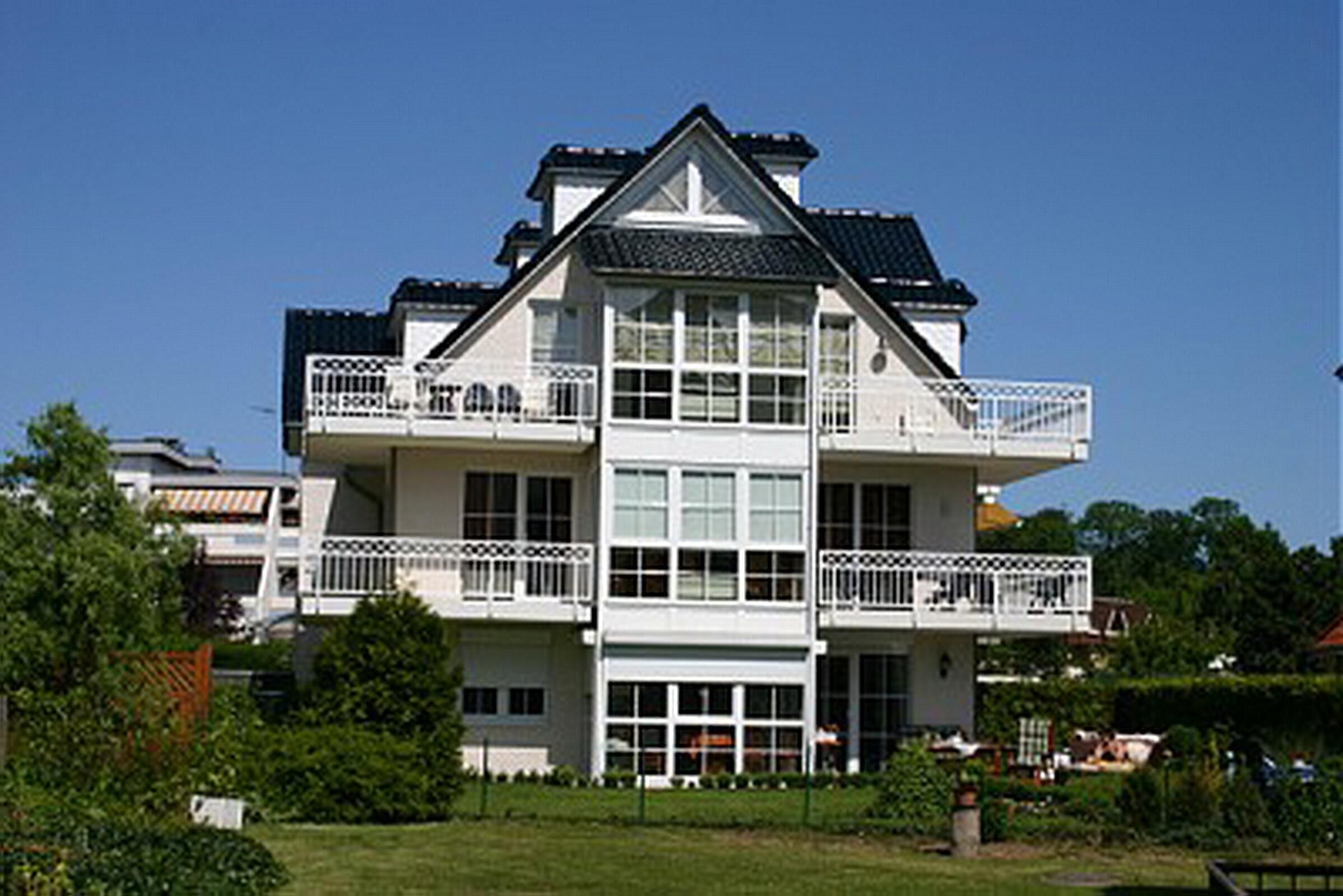 A two-story building with balconies, large windows, and a flat roof.